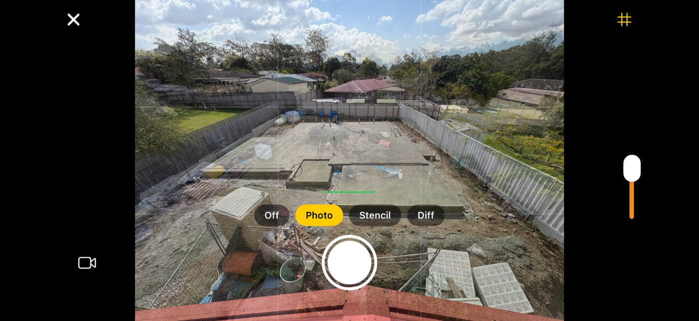 Plumb Daily's iPhone camera held sideways. A faint copy of the first photo, a mown backyard, shows over the live view of the same yard with a new concrete slab. Buttons for Off, Photo, Stencil and Diff sit above the shutter, with an opacity slider on the right.